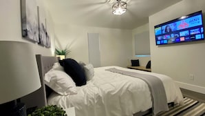 Una camera da letto moderna con un letto, una TV a parete e una lampada a sospensione.