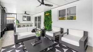 Un espace de détente moderne avec des canapés blancs, une table basse noire et un jardin vertical vert.