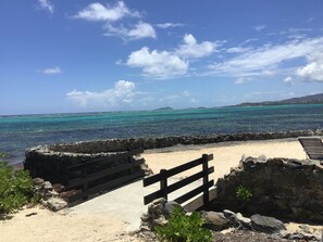 A beach with a stone wall and wooden benches.