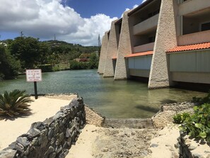 A building with a stone facade and a red-tiled roof, overlooking a body of water.
