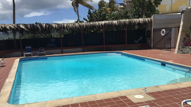 Piscina retangular com superfície de água azul cristalina, rodeada por um deck ladrilhado com espreguiçadeiras.