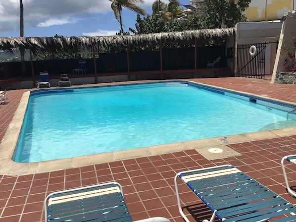 A rectangular swimming pool with a clear blue water surface, surrounded by a tiled deck with lounge chairs.