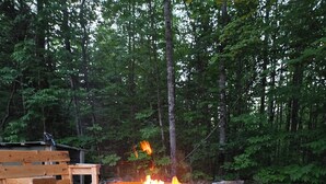 A campfire with a decorative metal fire pit surrounded by rocks and grass.