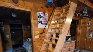 Een houten interieur met een wenteltrap, een bed, een keukenhoek en een waarschuwing voor beren.