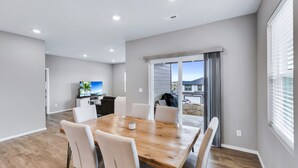 Una cucina moderna con TV a schermo piatto, tavolo da pranzo in legno e sedie bianche.