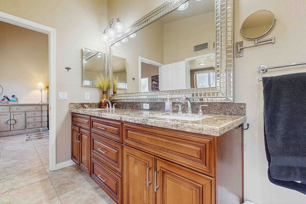 Une salle de bain avec un grand meuble-lavabo, un miroir et un porte-serviettes.