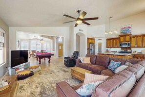 A spacious living room with a large flat-screen TV, a brown leather sofa, and a dining area with a pool table. - Private Pool, Yard & Pool Table! 'Avondale Abode' (Avondale)