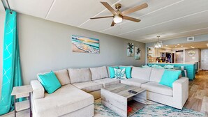 Ein modernes Wohnzimmer mit einem Ecksofa, einem Couchtisch und einem Deckenventilator.