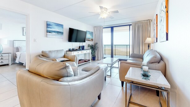 A modern living room with a sofa, a coffee table, a TV, and a balcony with curtains. - 2BR w/ Gulf-View Balcony: Suntide III - Unit 307 (South Padre Island)