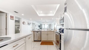 A modern kitchen with white cabinetry, a dishwasher, a refrigerator, and a central island with a sink. - 2BR w/ Gulf-View Balcony: Suntide III - Unit 307 (South Padre Island)