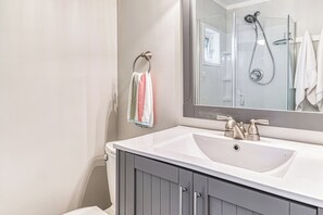 A bathroom with a white sink, a mirror, and a shower. - Oceanfront Studio w/ World-Class Views & Patio (Point Roberts)