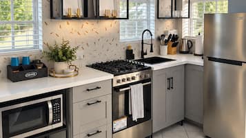 Et moderne køkken med indbygget komfur, ovn og køleskab, præget af et rent design og masser af naturligt lys.