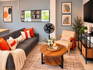 A modern living room with a grey sofa, a round wooden coffee table, and a beige armchair. - Lush & Beauty Modern Studio + Ocean View (Calibishie)