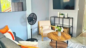 Una sala de estar moderna con un sofá gris, una mesa de centro de madera y un ventilador de techo negro.