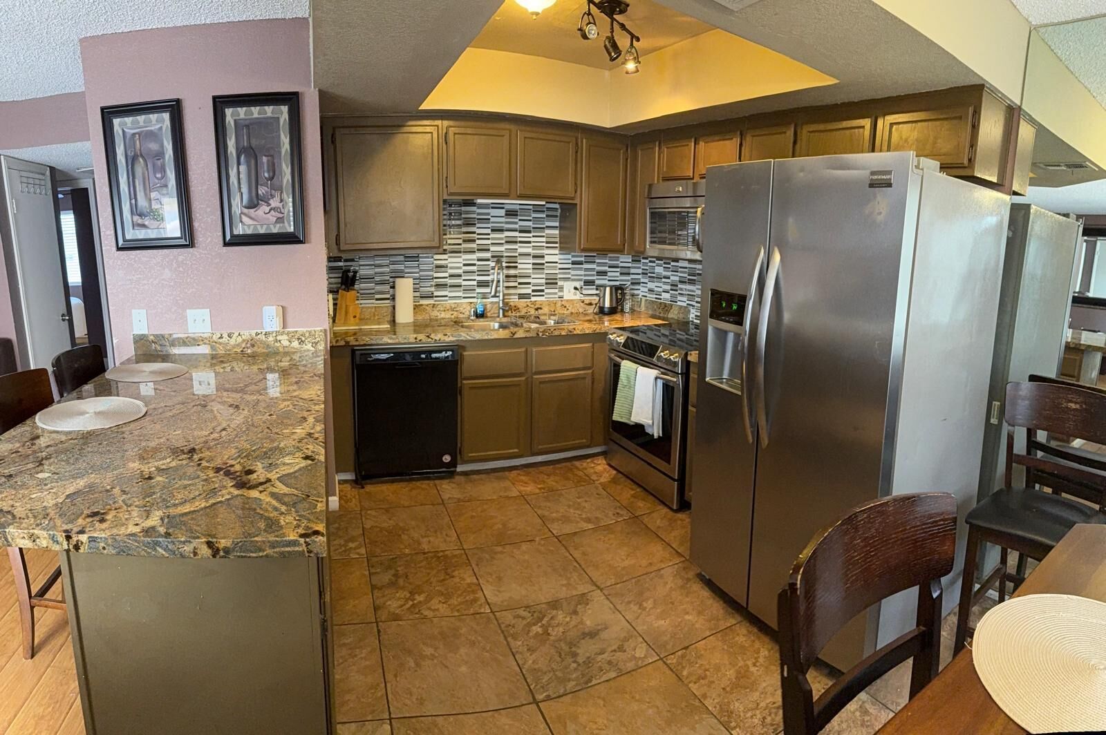 A compact kitchen with granite countertops, stainless steel appliances, and wooden cabinets.