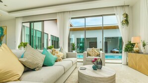 Un salon moderne avec un canapé, des fauteuils, une table basse et une vue sur une piscine.