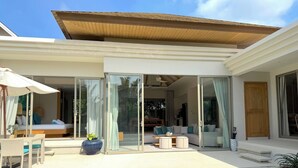 A modern house with a pool, sliding glass doors, and a covered patio area. - Luxury 3BR Pool Villa near Blue Tree - Bang Tao (Si Sunthon)