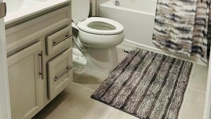 A bathroom with a toilet, sink, vanity, and a shower area with a curtain.