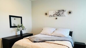 A bedroom with a bed, a nightstand, a mirror, and wall art.