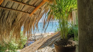 Ein Gebäude mit einem Strohdach und Blick auf Strand und Meer.