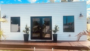 A modern white building with a dark door, two potted plants, and a wooden deck. - Tiny Mansion in Naples. 5 mins to Beach (Naples)