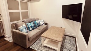 A modern living room with a grey sofa, patterned rug, and a wooden coffee table. - Tiny Mansion in Naples. 5 mins to Beach (Naples)