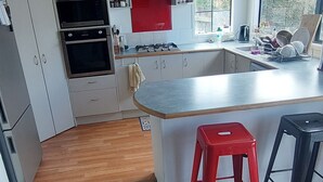 A modern kitchen with white cabinets, a red accent wall, and a large window. - Located 5 mins drive from the town.  Pets are not allowed. (Te Awamutu)