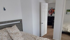 A bedroom with a large bed, a door leading to another room, and a ceiling light fixture. - Located 5 mins drive from the town.  Pets are not allowed. (Te Awamutu)