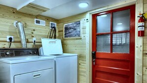 A laundry area with a red door, a white washing machine, and a vent on the wall. - Cozy 2-bedroom home in Oak Ridge - 1940s themed (Oak Ridge)