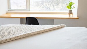 Un dormitorio con una cama grande, un escritorio de madera y una ventana con vista a árboles.