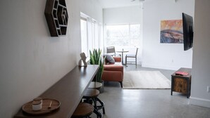 Una sala de estar moderna con una mesa de madera alargada, un sofá y un televisor montado en la pared.