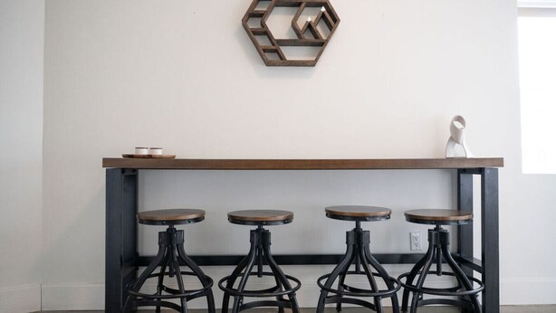 Una zona de bar con mostrador de madera y cuatro taburetes.