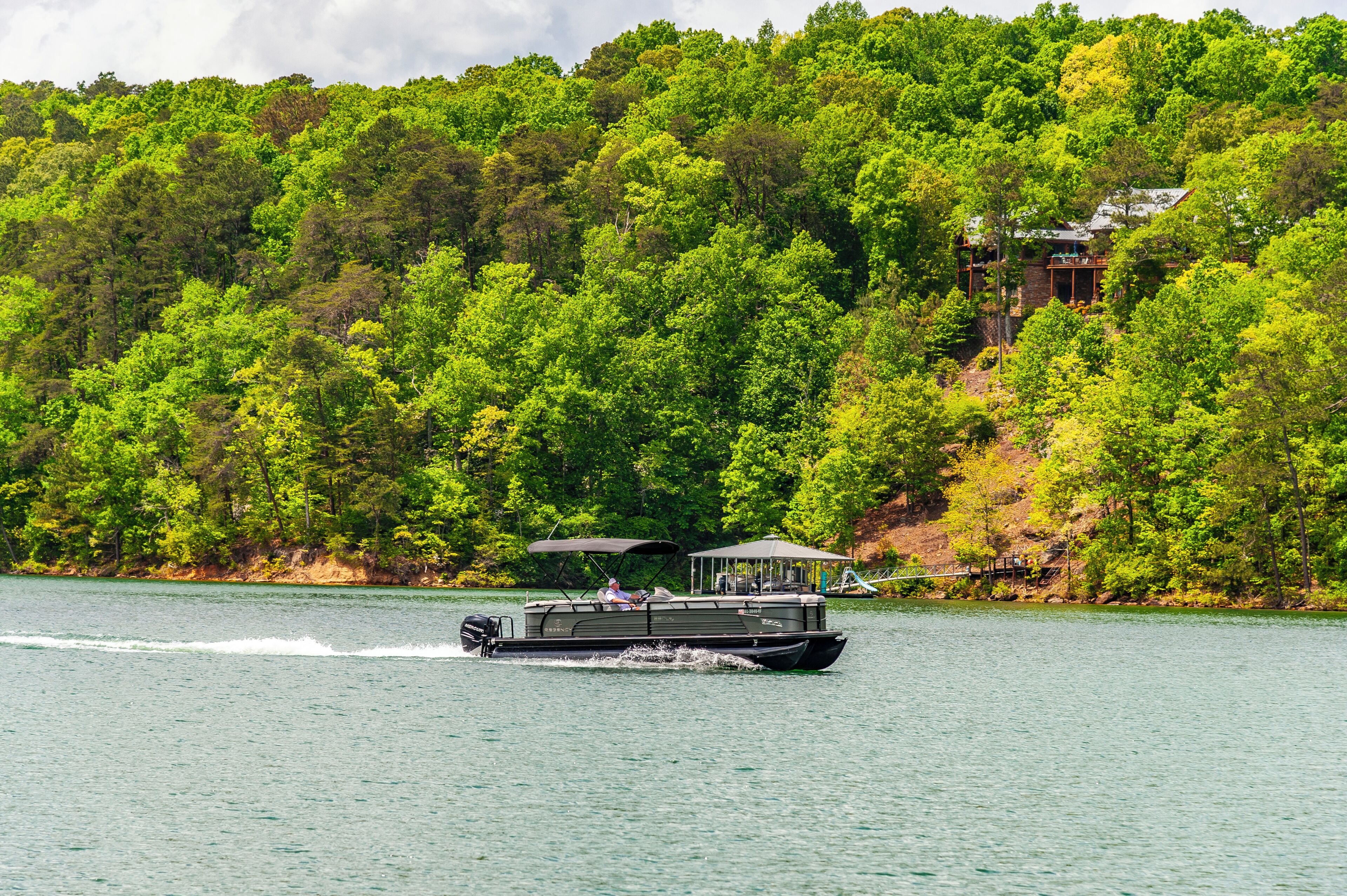 A boat on a lake with a forested hillside in the background.