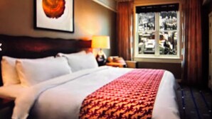 A hotel room with a large bed, a headboard, a nightstand, a lamp, and a window with curtains. - Special Discount: Stay on Main Street for New Year's in 2 Bedroom Villa (Park City)