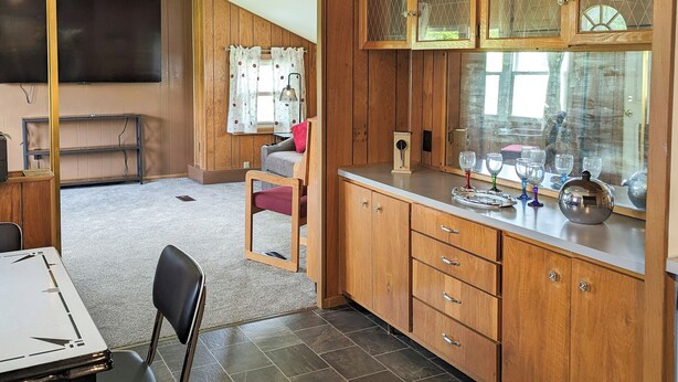 Una cucina compatta con mobili in legno, un tavolo da pranzo e una TV a parete.