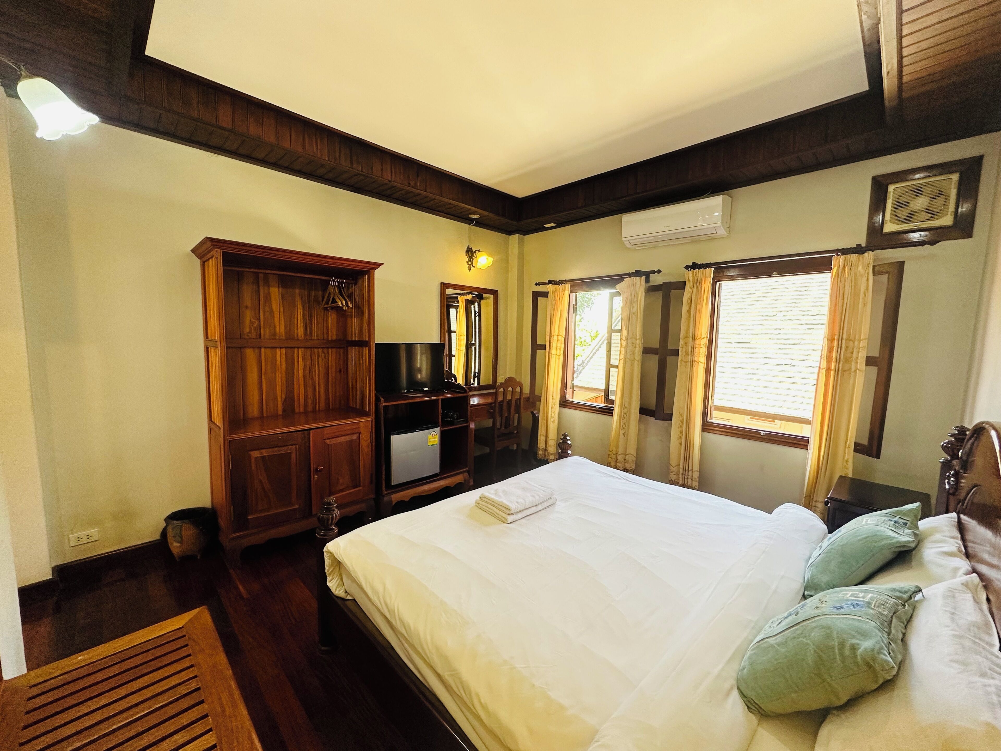 Une chambre à coucher avec un lit, une armoire en bois, une télévision et un bureau.