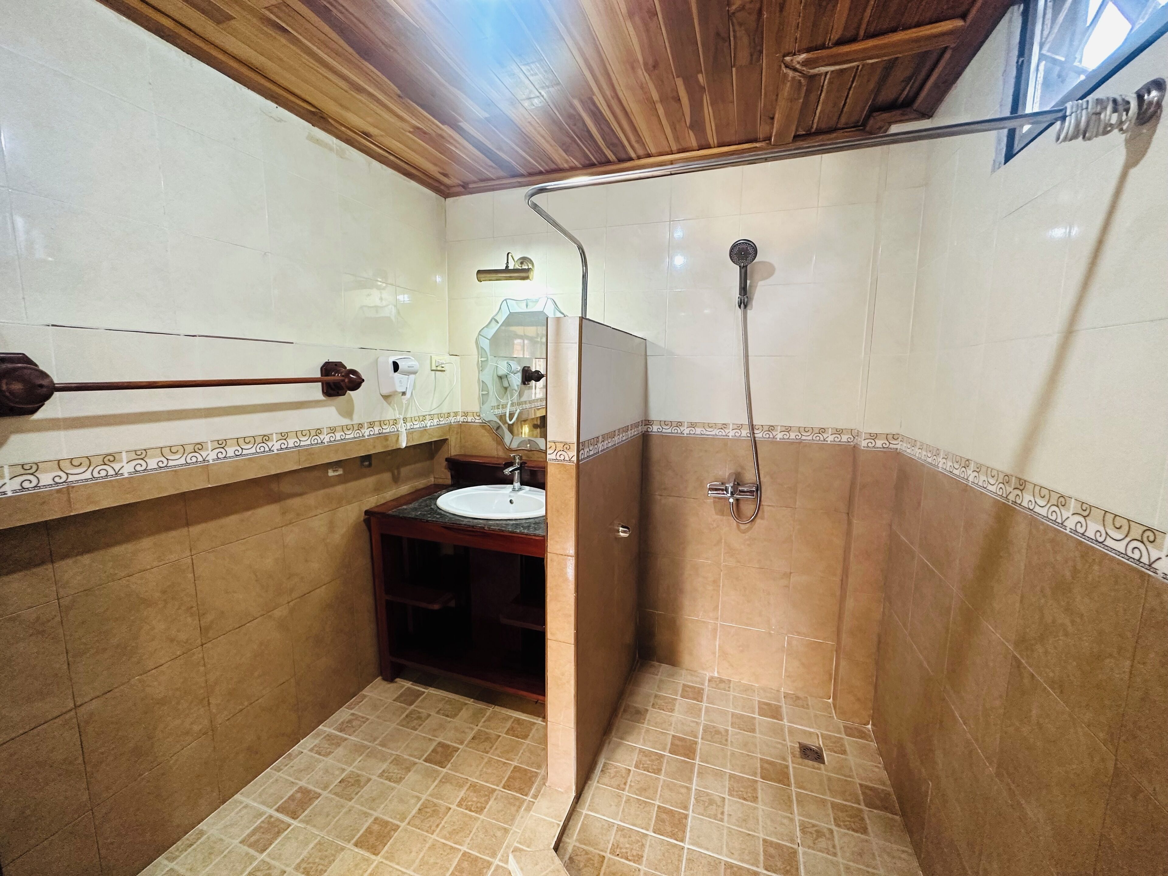 Une salle de bain avec un plafond en bois, un lavabo, un miroir et une douche.