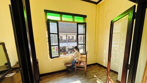 Ein Zimmer mit großem Fenster, Holzboden und einem Stuhl am Fenster.