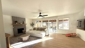 A spacious living room with a fireplace, a sofa, a coffee table, and a large window. - NEW 4BR Cozy Home close to everything! Pet-friendly & remote work friendly (Reno)