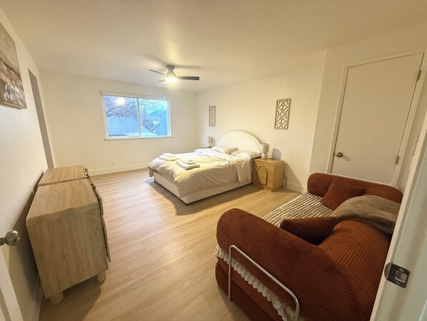 A bedroom with a bed, a nightstand, a dresser, a window, and a door. - NEW 4BR Cozy Home close to everything! Pet-friendly & remote work friendly (Reno)