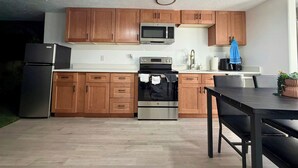 Une cuisine moderne avec des meubles en bois, des appareils en acier inoxydable et un coin repas comprenant une table et des chaises.