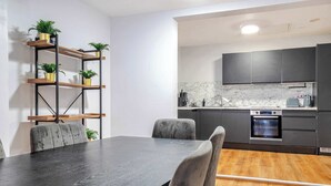 A modern kitchen with dark cabinets, a marble backsplash, and a built-in oven. - Host Stay Apartment 1 Stanley Street (Liverpool)