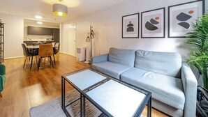A modern living room with a grey sofa, a glass coffee table, and a dining area with a table and chairs. - Host Stay Apartment 1 Stanley Street (Liverpool)