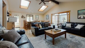 A spacious living room with a high ceiling, a dining area, and large windows.