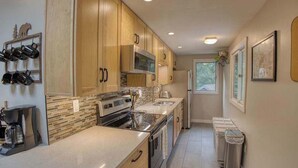 A modern kitchen with wooden cabinets, a built-in oven, and a coffee maker.