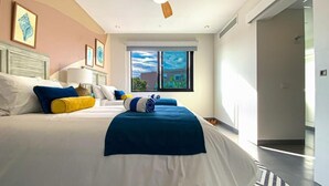 Moderni hotellihuone, jossa on suuri sänky, kattotuuletin ja näkymä ulos.