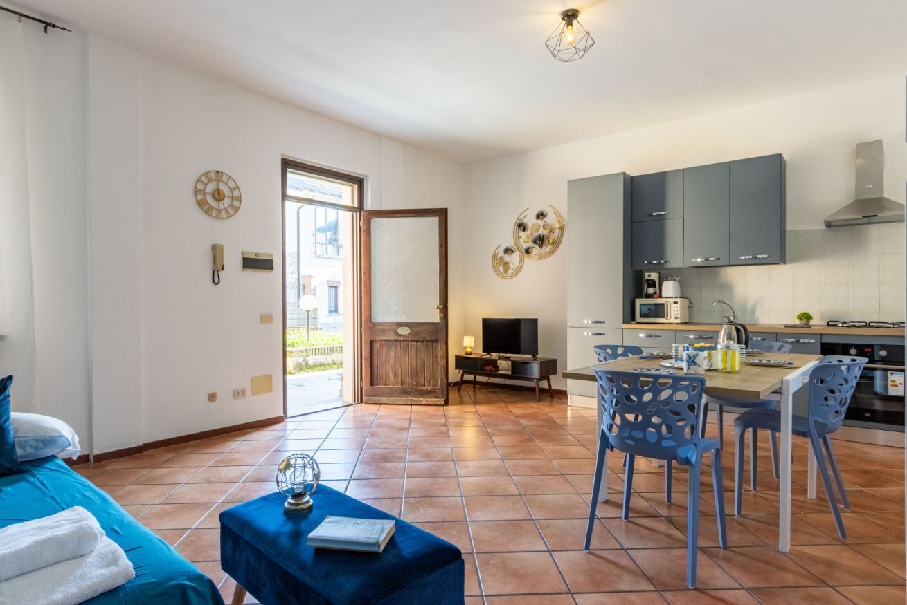 Ein modernes Wohnzimmer mit einer Couch, einem Couchtisch und einem Fernseher. Es gibt einen Essbereich mit Tisch und Stühlen. Der Raum verfügt über ein großes Fenster und eine Tür, die nach draußen führt.