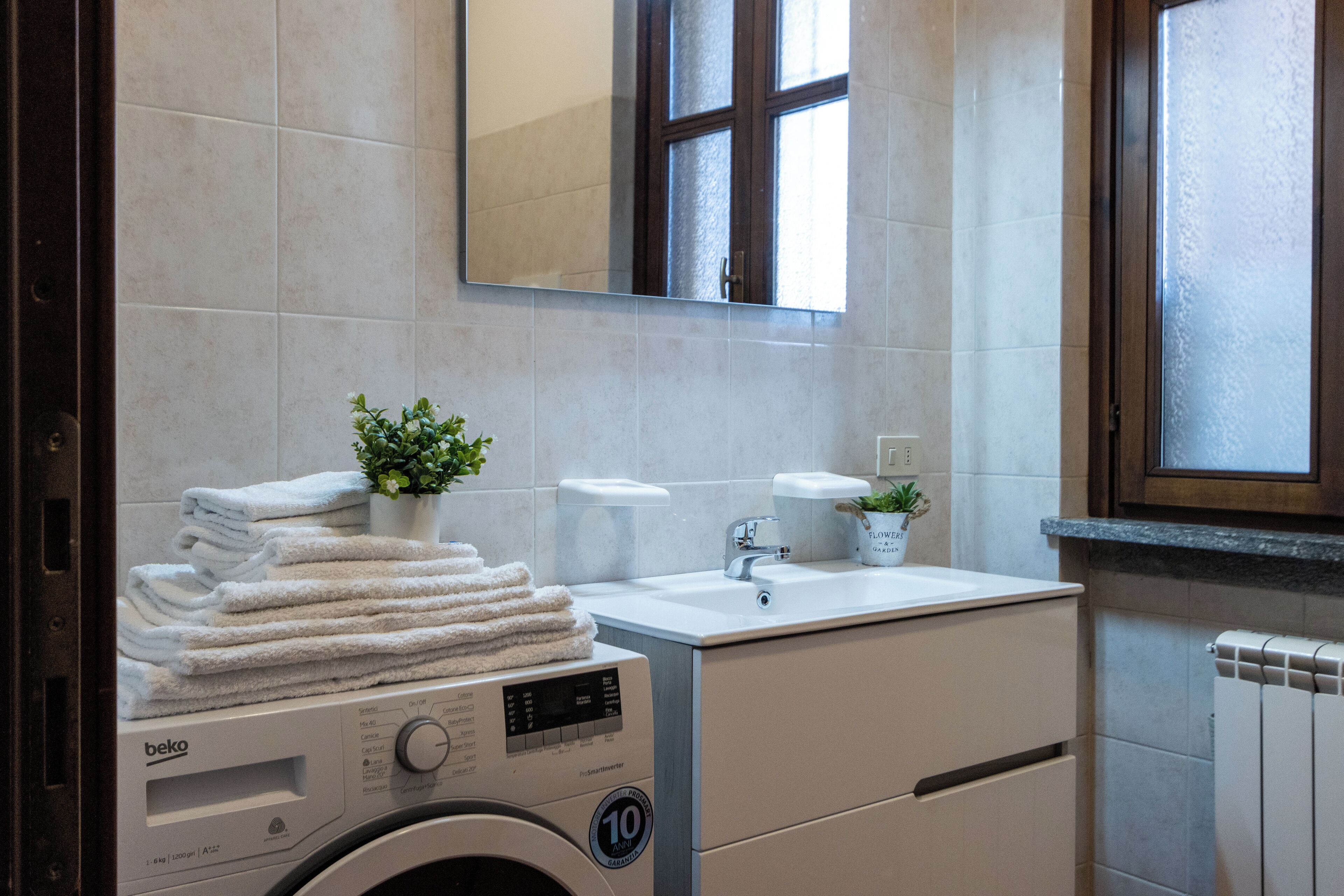 Un bagno moderno con lavatrice, lavandino e specchio.