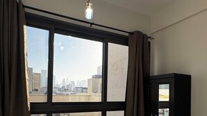 Hotellihuone, jossa on suuri ikkuna, sänky, vaatekaappi ja kattovalaisin.
