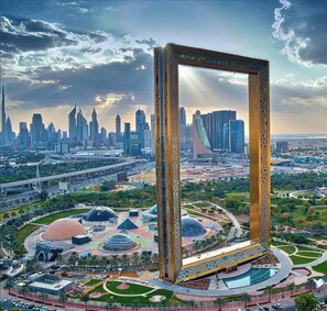 A large, ornate frame structure in a park with a cityscape in the background.